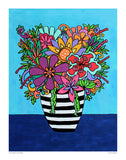 black and white striped vase filled with colorful flowers in bright pinks, purples, oranges, and greens against a turquoise background and a dark blue table.